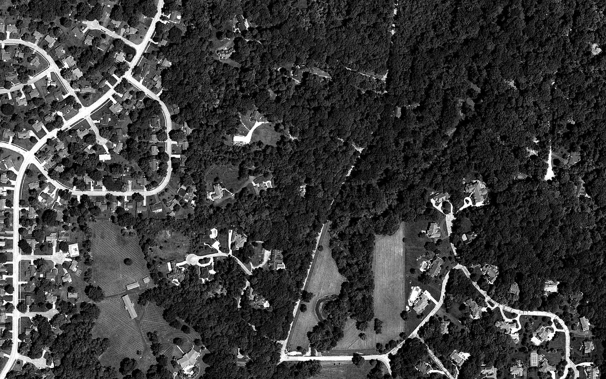 Black and white aerial photo of the woods and fields around 7710 Sargent Road, Indianapolis, with a marker on Estate 77.